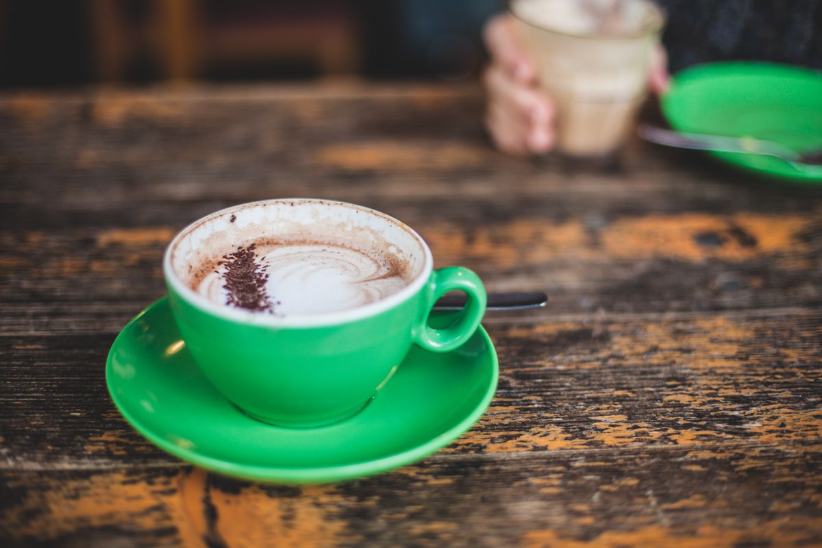 A bright green matcha cappuccino on a rustic table